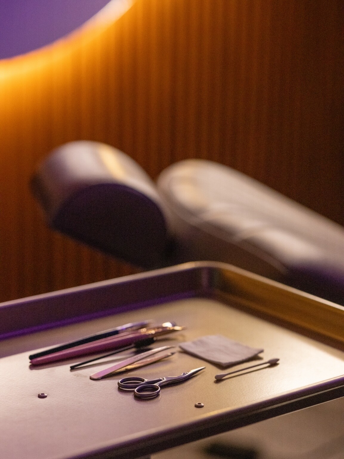 Brow tools laid out on a tray in the purple-lit studio